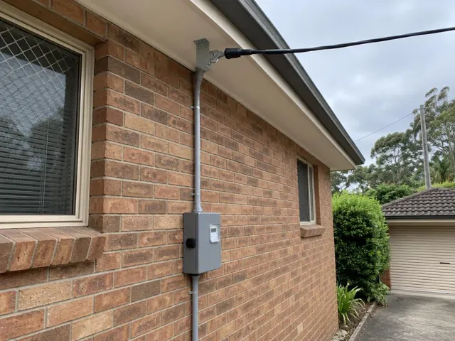 Brick house exterior with overhead service line and meter box on the wall in Frenchs Forest